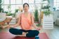Young woman doing stretching exercise in front of laptop at home