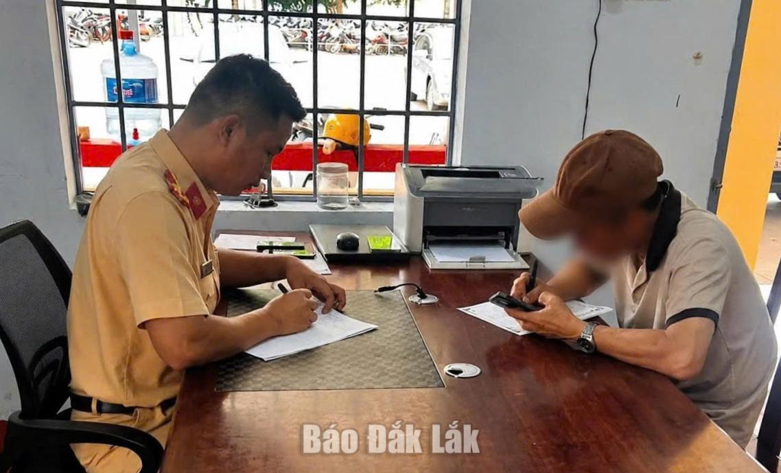 Cán bộ CSGT lập biên bản xử phạt hành chính tài xế dừng xe gây cản trở giao thông.